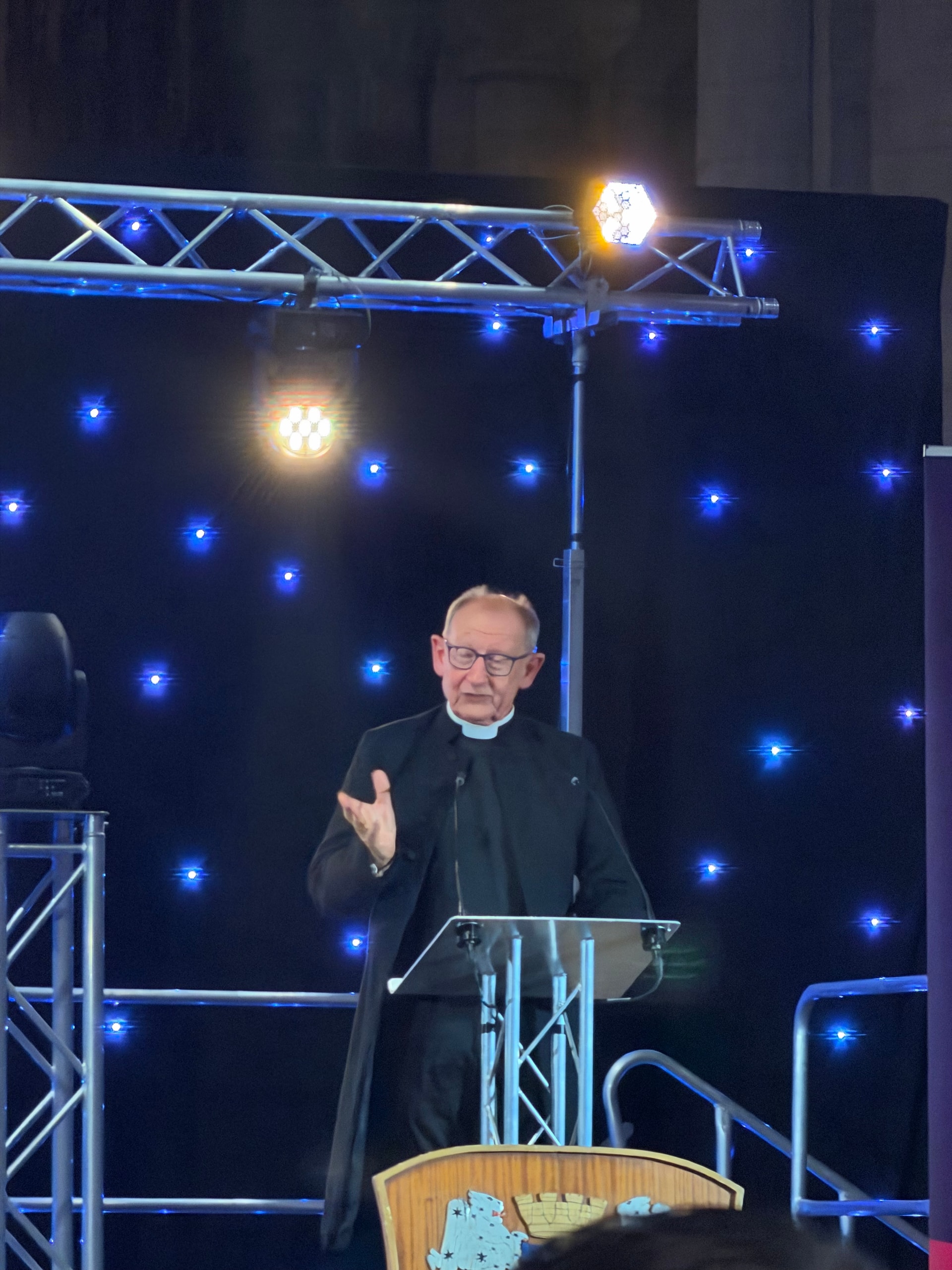 Clergyman speaking from the awards lectern against a star-lit backdrop