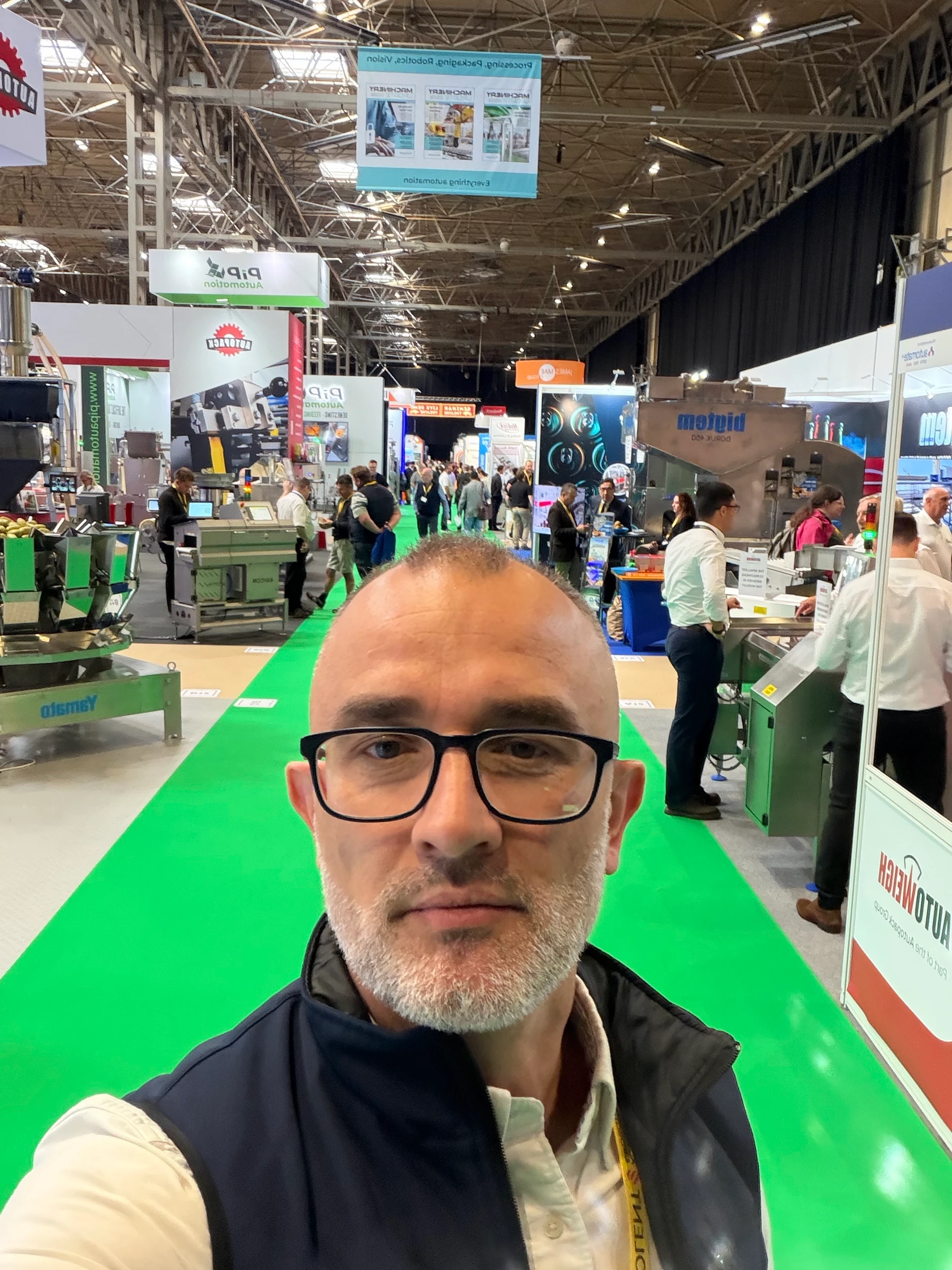 Visitor taking a selfie on a green-carpeted exhibition aisle