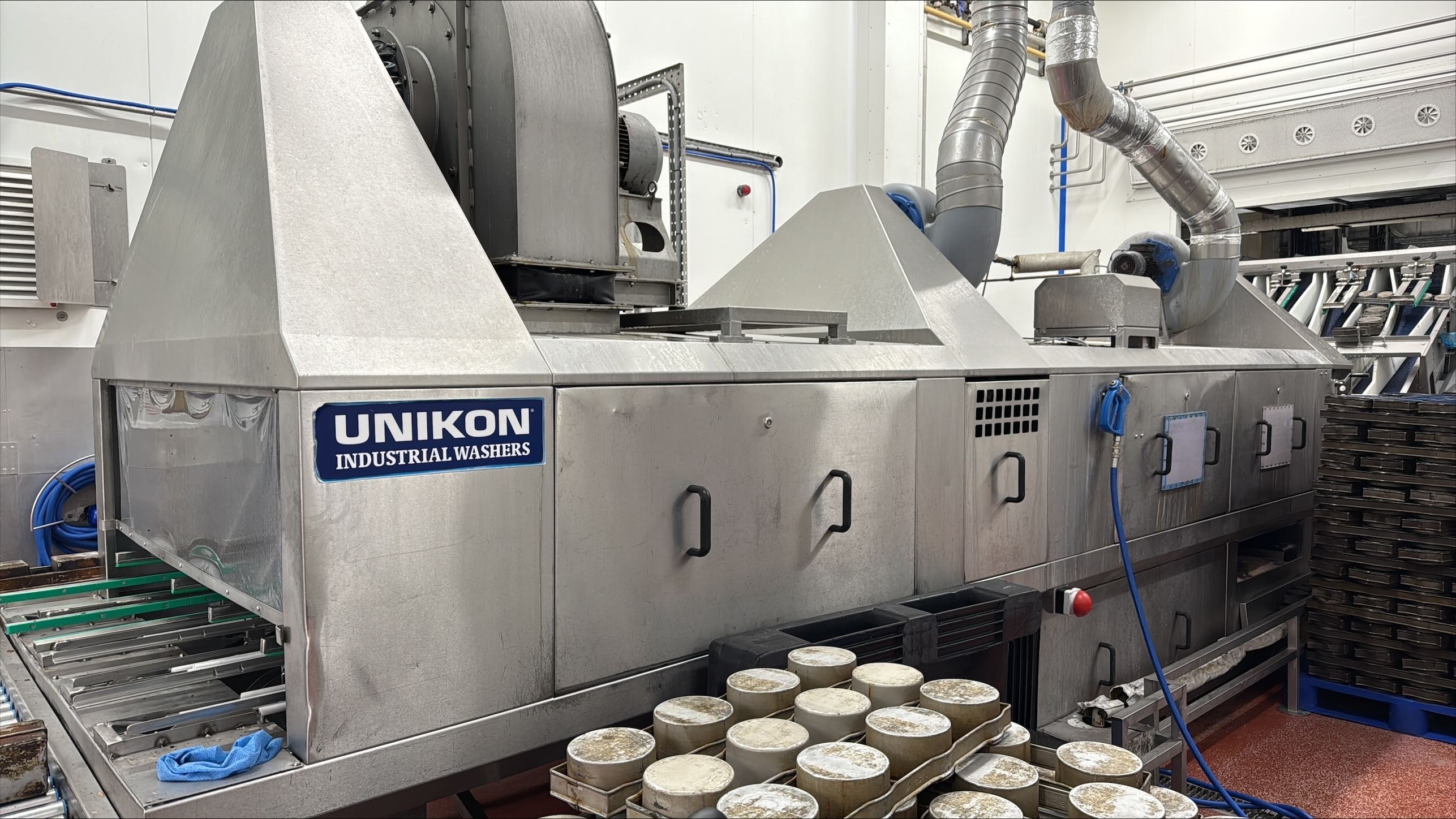TYPE: photograph
CONTENT: The image shows a large stainless steel industrial washing machine, branded "UNIKON INDUSTRIAL WASHERS", in a <a href=