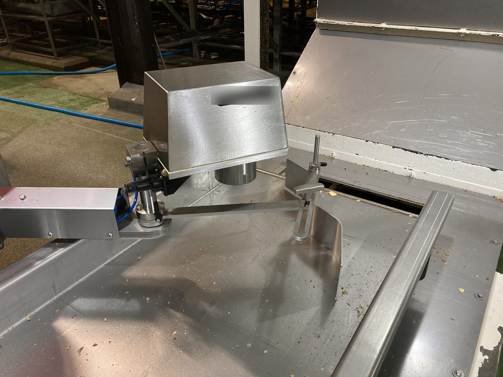 A close photograph shows the protected inline sensor head mounted over the product conveyor at the fryer outlet. The installation is associated with real-time measurement of product moisture and oil content before the controller adjusts fryer temperature and line speed.